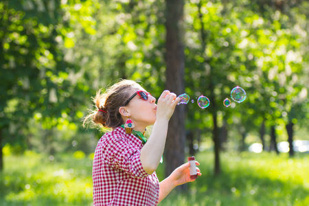 Cheerful beautiful brunette girl blowing soap bubbles outdoor.の写真素材