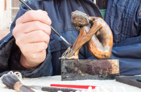 Hands of sculptor hold sculpture and clean it with brush.の写真素材