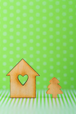Wooden sign of house with hole in form of heart and little Christmas tree on green background verticalの写真素材