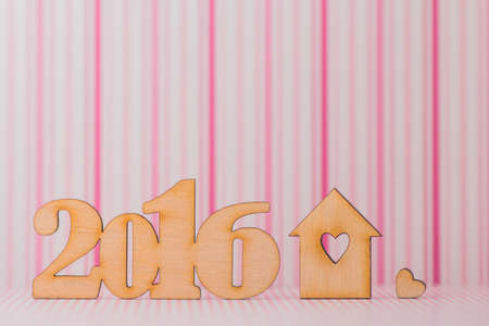 Wooden inscription of 2016 year and house with hole in for of heart on pink striped background.の写真素材