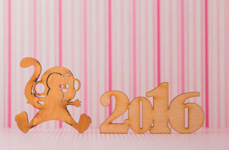 Wooden sign of monkey and inscription of 2016 year on pink striped background. Concept of Eastern horoscope.の写真素材