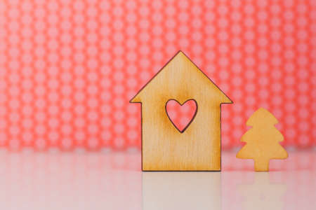 Wooden sign of house with hole in form of heart and little Christmas tree on red background horizontalの写真素材