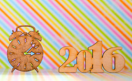 Wooden sign of alarm clock and inscription of 2016 year on rainbow striped background.の写真素材