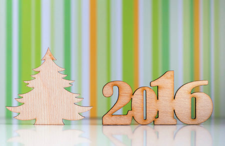 Wooden sign of 2016 year and Christmas tree on green striped background.
