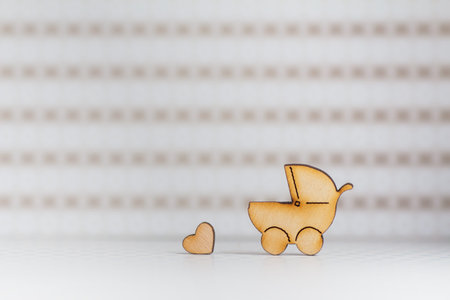 Wooden icon of baby carriage and little heart on light background.