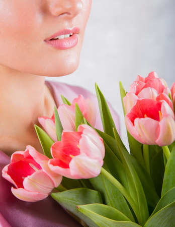 Part of beautiful young girl`s face with pink tulips bouquet.の写真素材