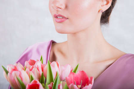 Part of beautiful young girl`s face with pink tulips bouquet.の写真素材