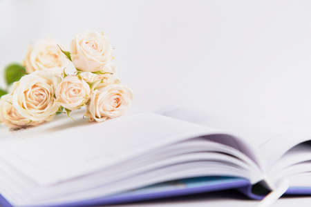 Bouquet of creamy roses lying on open notebook.の写真素材