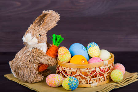 Wicker Easter bunny with Easter eggs in basket on dark wooden background.の写真素材