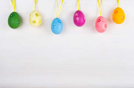 Colorful Easter eggs hanging on white wooden background.の写真素材