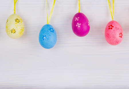 Colorful Easter eggs hanging on white wooden background.の写真素材