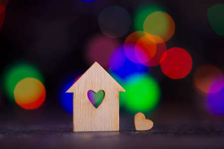 Wooden house with hole in form of heart with garland lights on colorful bokeh background.の写真素材