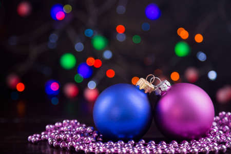 Blue and pink Christmas balls and beads with garland lights on colorful bokeh background.の写真素材