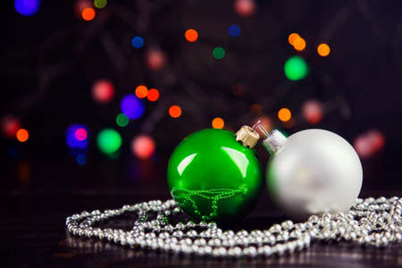 Green and white Christmas balls and beads with garland lights on colorful bokeh background.の写真素材