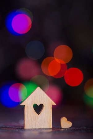 Wooden house with hole in form of heart with garland lights on colorful bokeh background.の写真素材