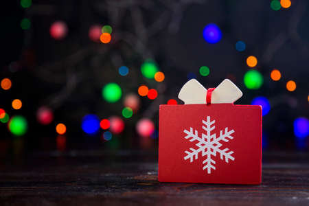 Wooden red gift with snowflake with garland lights on colorful bokeh background.の写真素材