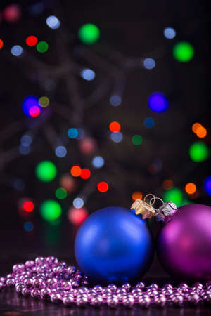 Blue and pink Christmas balls and beads with garland lights on colorful bokeh background.の写真素材