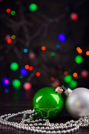 Green and white Christmas balls and beads with garland lights on colorful bokeh background.の写真素材