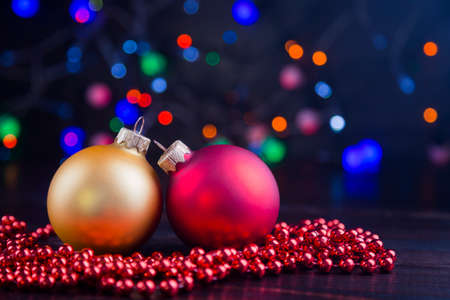 Red and golden Christmas balls and beads with garland lights on colorful bokeh background.の写真素材