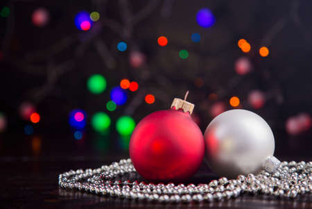 Red and silver Christmas balls and beads with garland lights on colorful bokeh background.の写真素材