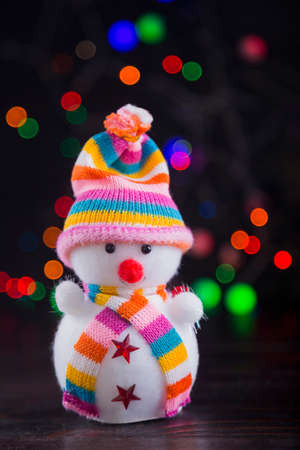 Toy cute snowman with garland lights on colorful bokeh background.の写真素材
