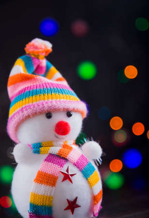 Toy cute snowman with garland lights on colorful bokeh background.の写真素材