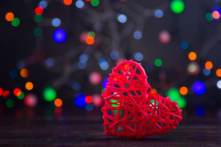 Wicker red heart with garland lights on colorful bokeh background.の写真素材