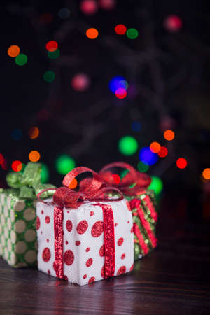 Three gift boxes with garland lights on colorful bokeh background.の写真素材
