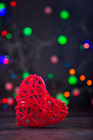 Wicker red heart with garland lights on colorful bokeh background.の写真素材