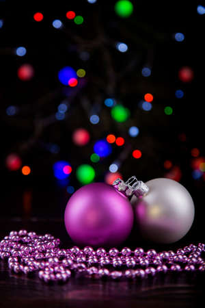 Pink and white Christmas balls and beads with garland lights on colorful bokeh background.の写真素材