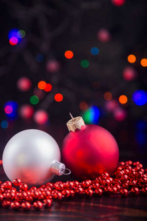 White and red Christmas balls and beads with garland lights on colorful bokeh background.の写真素材