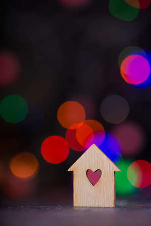 Wooden house with hole in form of heart with garland lights on colorful bokeh background.の写真素材