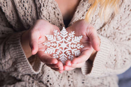 Young female hands holding white snowflake.の写真素材