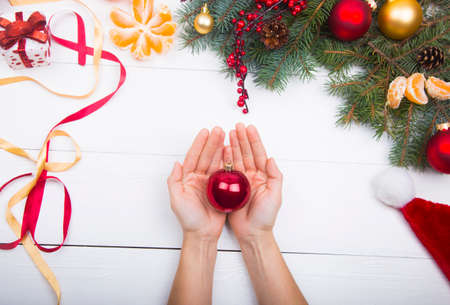 Hands holding red ball on Christmas decorations background.の写真素材