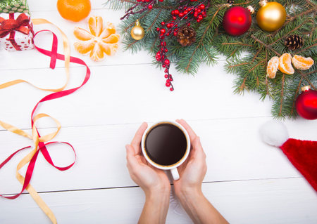 Hands holding coffee cup on Christmas decorations background.の写真素材