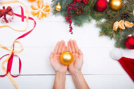 Hands holding golden ball on Christmas decorations background.の写真素材