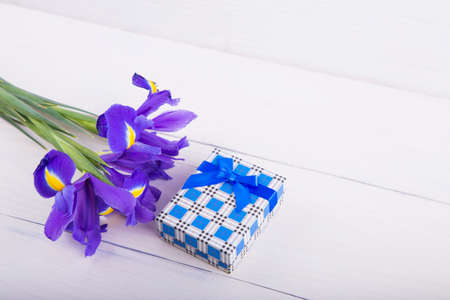 Bouquet of beautiful irises with gift box on white wooden background.の写真素材