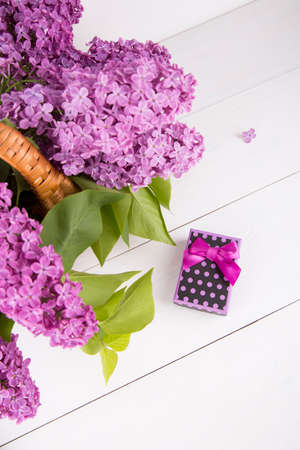 Bouquet of lilac in wicker basket with purple gift box on white background.の写真素材