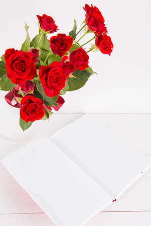 Bouquet of red roses with open notebook on white background.の写真素材
