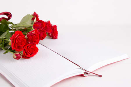 Bouquet of red roses with open notebook on white background.の写真素材