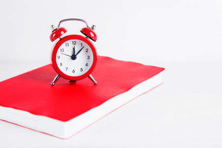 Red little alarm clock with notebook on white background.の写真素材