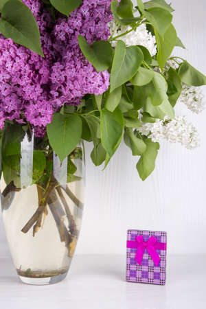 Bouquet of lilac in vase with purple gift box on white background.の写真素材