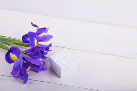 Bouquet of beautiful irises with gift box on white wooden background.の写真素材