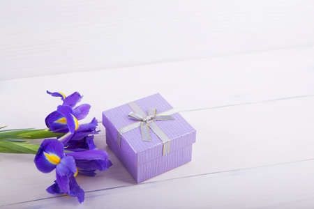 Bouquet of beautiful irises with gift box on white wooden background.の写真素材