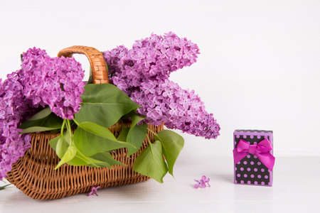 Bouquet of lilac in wicker basket with purple gift box on white background.の写真素材