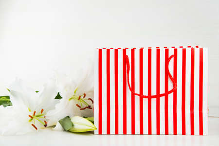 Bright shopping bag with bouquet of white lilies on white background.の写真素材