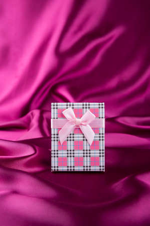 Gift box on curvy satin fabric background.の写真素材