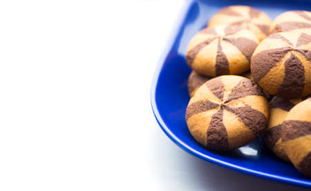 Short pastry cookies with addition of chocolate in blue plate on white background.の写真素材