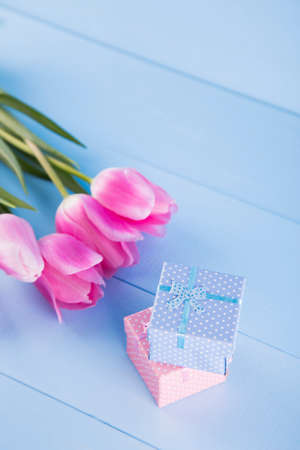 Bouquet of tender pink tulips with two gift boxes on light blue wooden backgroundの写真素材