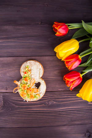 Bouquet of red and yellow tulips with 8 march honey-cake on wooden background.の写真素材